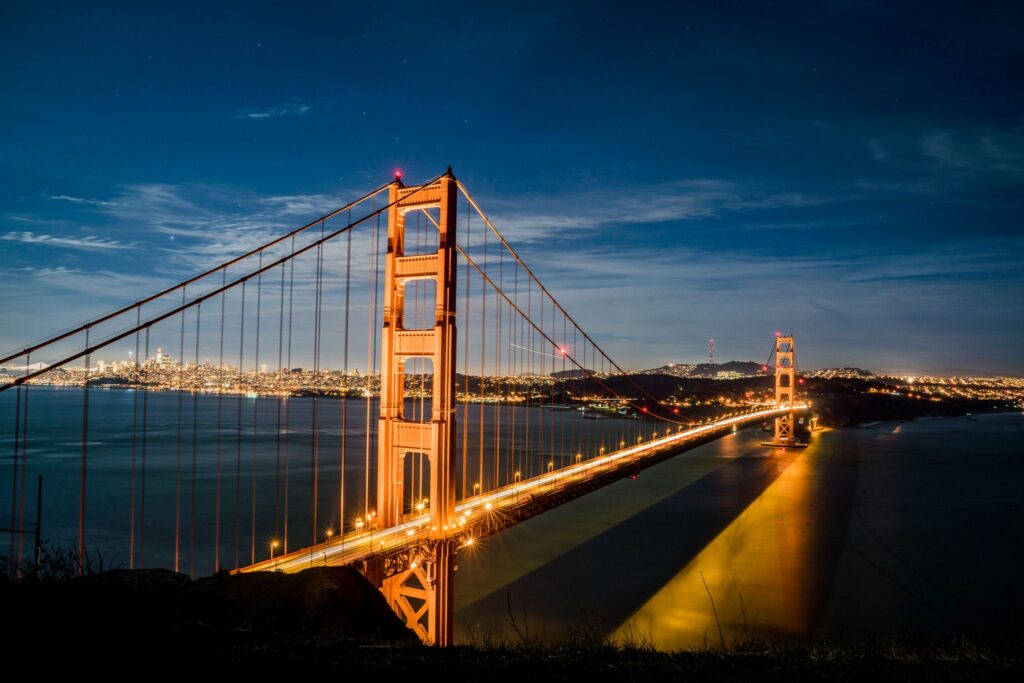 Stunning view of the illuminated Golden Gate Bridge at dusk against a vibrant cityscape.