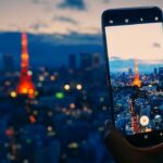 Night view of Tokyo Tower photographed through a smartphone, showcasing city lights and skyline.