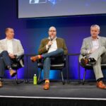Sierra Space Defense SVP Erik Daehler speaks into a microphone between two fellow panelists on the on-orbit servicing panel at Silicon Valley Space Week 2026.
