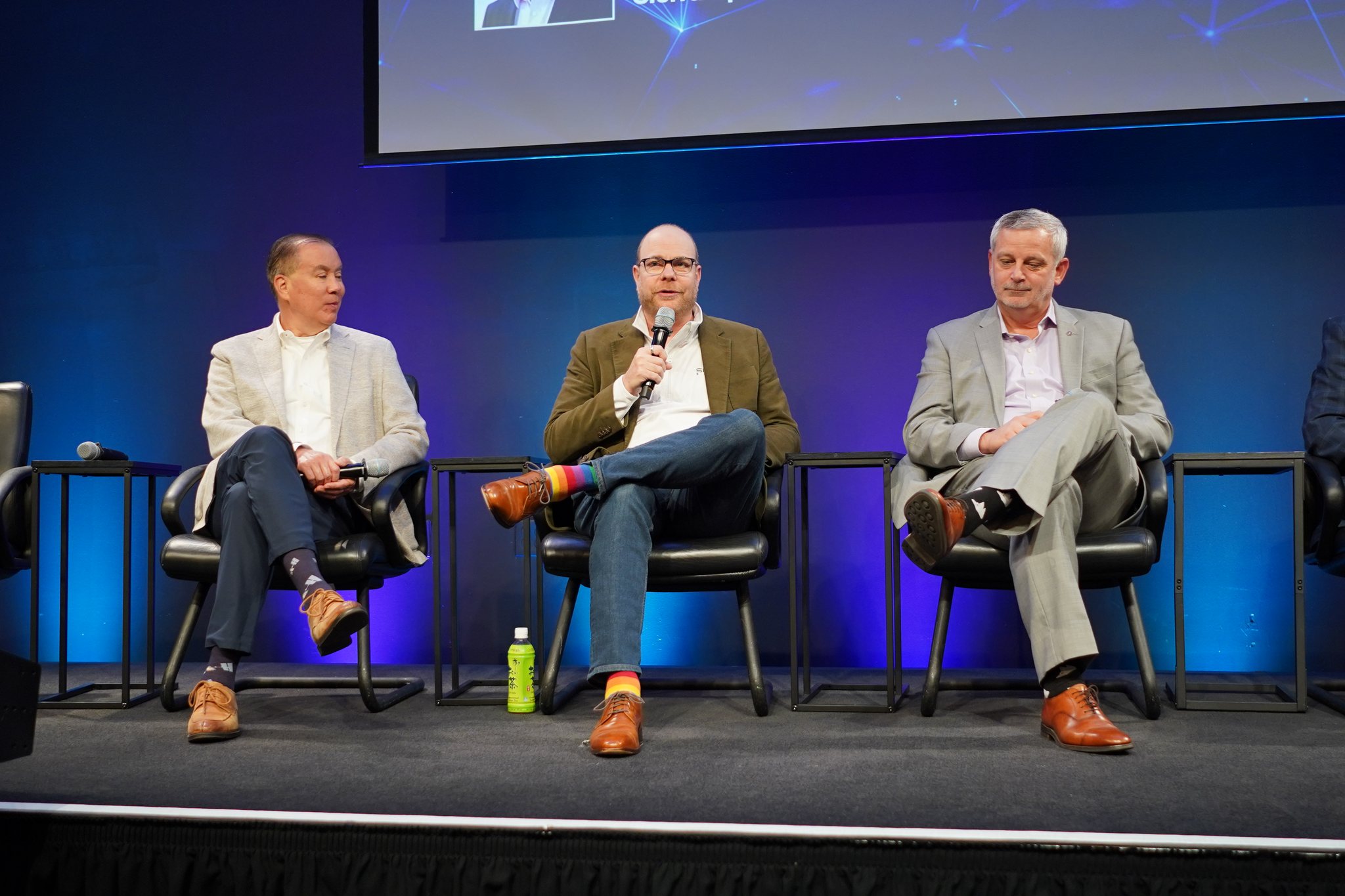 Sierra Space Defense SVP Erik Daehler speaks into a microphone between two fellow panelists on the on-orbit servicing panel at Silicon Valley Space Week 2026.