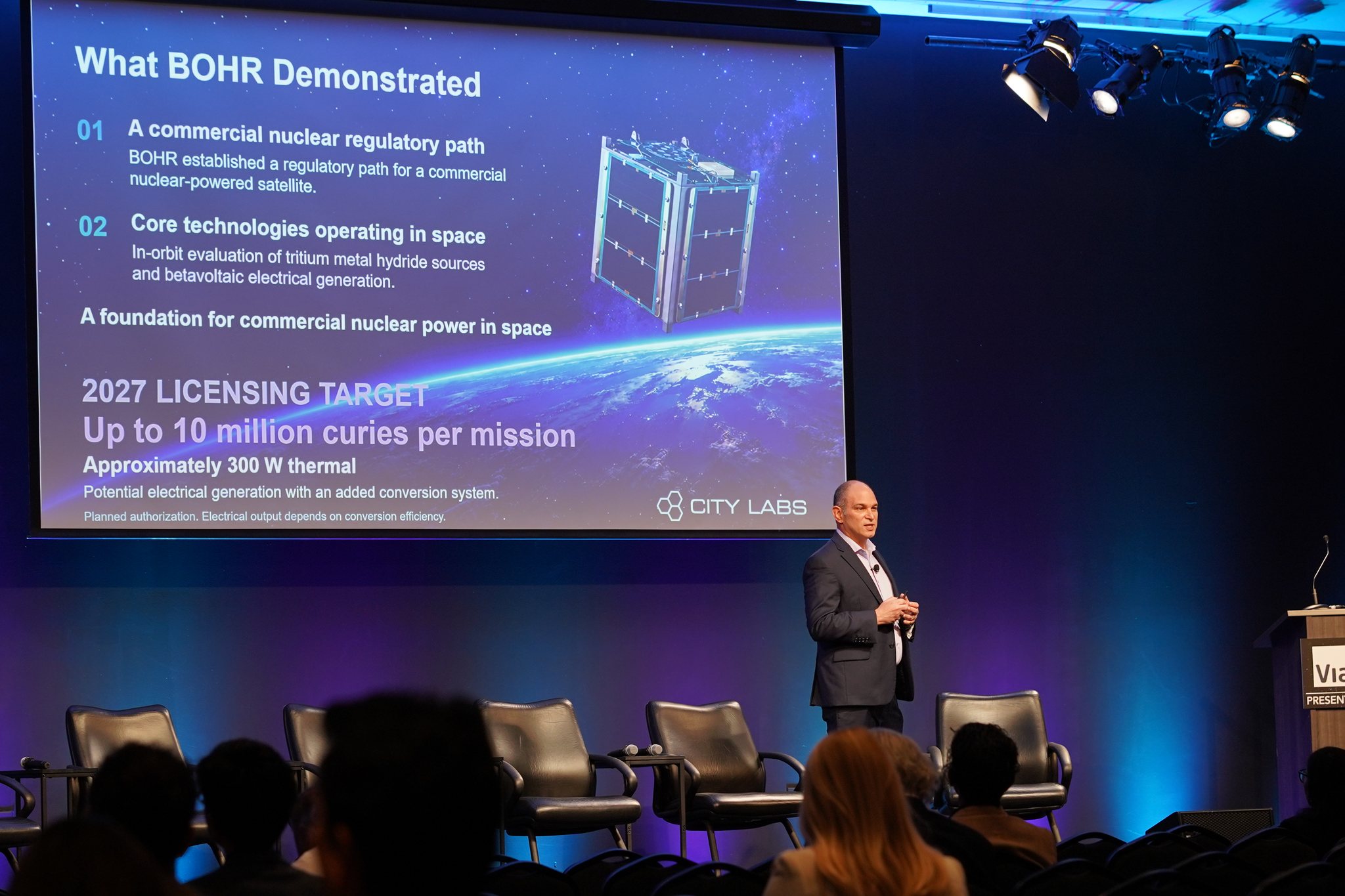 City Labs CEO Peter Cabauy presents at the MilSat Symposium in front of a slide reading “What BOHR Demonstrated” and “2027 licensing target: up to 10 million curies per mission.”